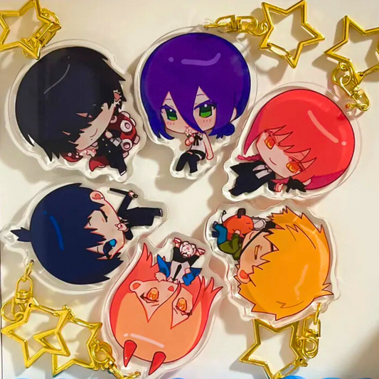 A collection of chibi-style acrylic keychains featuring characters from the anime Chainsaw Man, displayed against a white background with decorative gold stars.